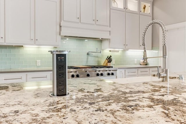 kitchen with white cabinetry, light stone countertops, backsplash, and extractor fan