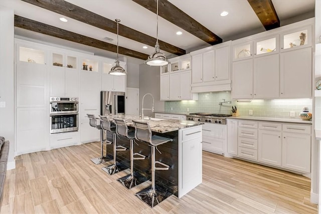 kitchen with beamed ceiling, a sink, a kitchen breakfast bar, backsplash, and appliances with stainless steel finishes