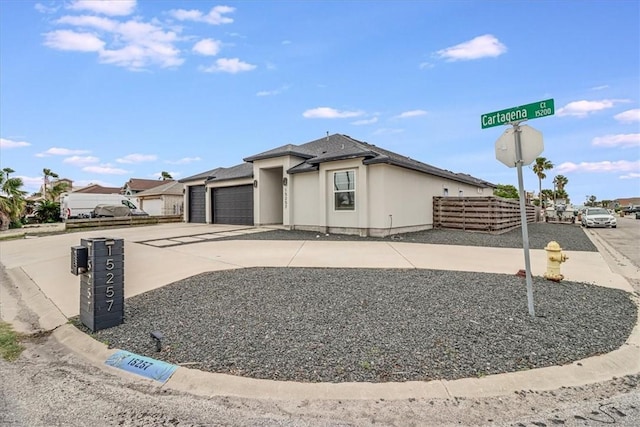 view of front of home featuring concrete driveway, stucco siding, an attached garage, and fence