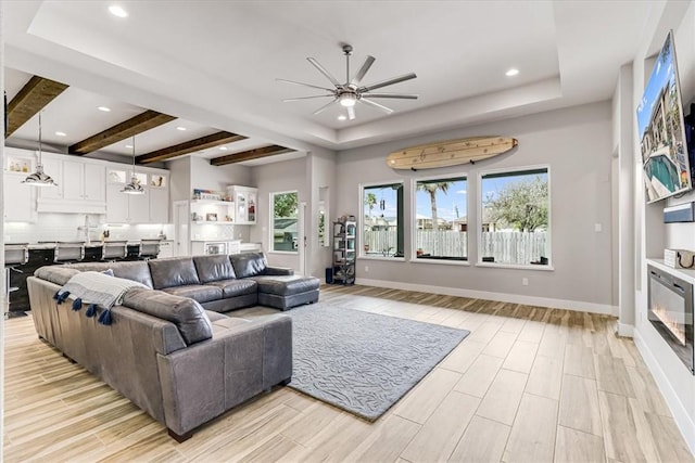 living room featuring recessed lighting, a raised ceiling, a ceiling fan, and light wood finished floors
