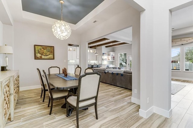 dining area with a chandelier, light wood-style floors, baseboards, visible vents, and a tray ceiling