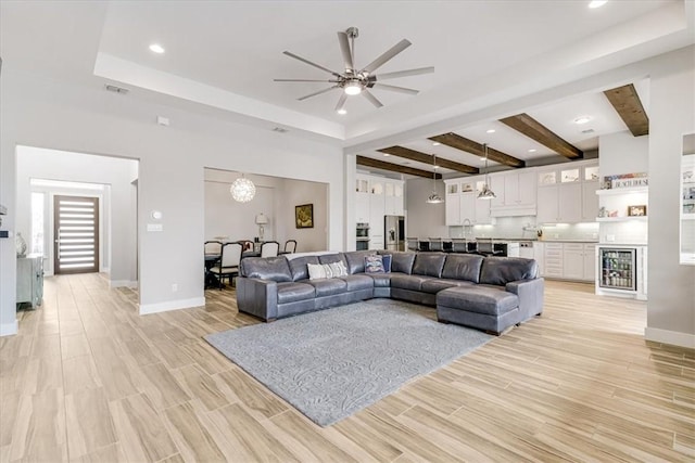 living area with visible vents, light wood-type flooring, a ceiling fan, and baseboards