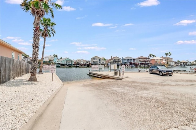 dock area featuring fence, a residential view, and a water view