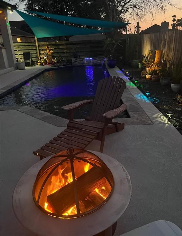 pool at dusk featuring a fenced backyard, a fenced in pool, and a patio area