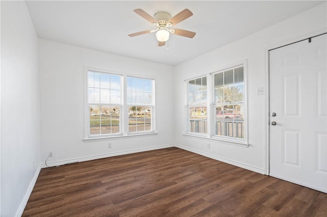 spare room featuring dark wood-style floors, a wealth of natural light, baseboards, and a ceiling fan