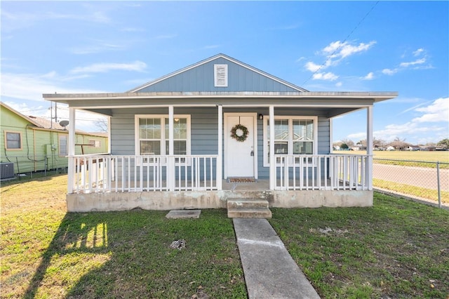 bungalow with a porch, fence, a front lawn, and cooling unit