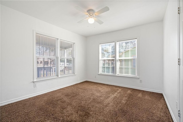 spare room featuring ceiling fan, dark colored carpet, and baseboards