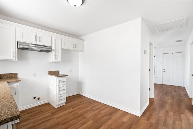 kitchen featuring baseboards, white cabinets, dark stone countertops, dark wood-style flooring, and under cabinet range hood