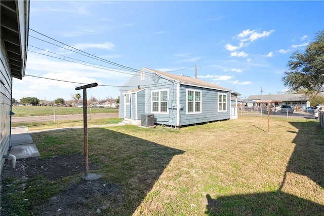 view of property exterior featuring an outbuilding, a yard, cooling unit, and fence