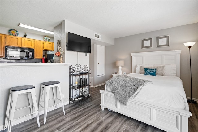 bedroom featuring dark hardwood / wood-style flooring, black fridge, and a textured ceiling