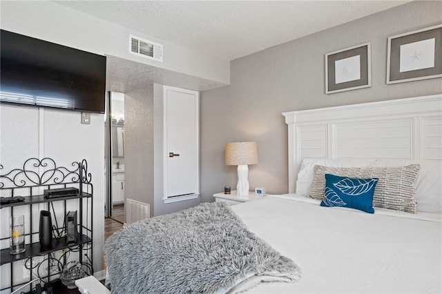 bedroom with connected bathroom and a textured ceiling