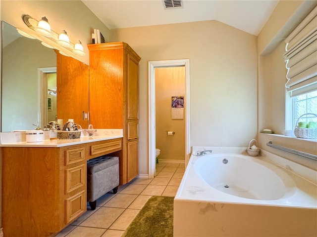 bathroom with tile patterned floors, vanity, vaulted ceiling, a bathing tub, and toilet