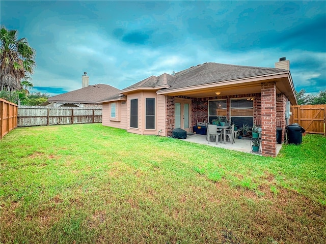 rear view of house featuring a yard and a patio