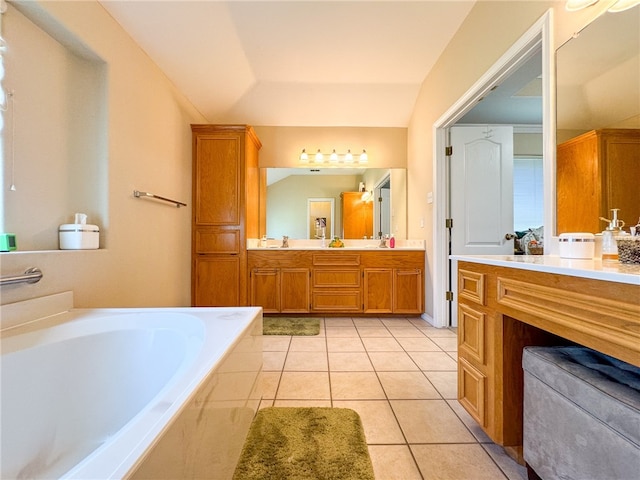 bathroom with tiled bath, tile patterned flooring, lofted ceiling, and vanity