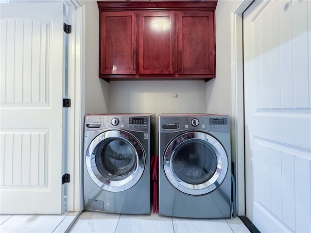 washroom featuring washing machine and dryer, cabinets, and light tile patterned floors