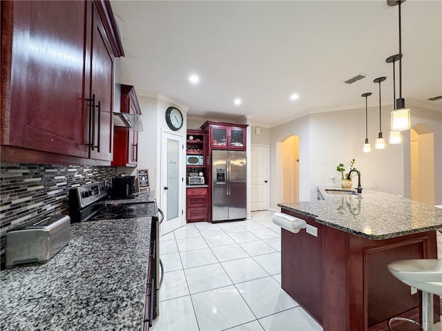 kitchen with tasteful backsplash, decorative light fixtures, stainless steel refrigerator with ice dispenser, black / electric stove, and a breakfast bar