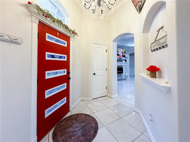 tiled entryway with an inviting chandelier and crown molding