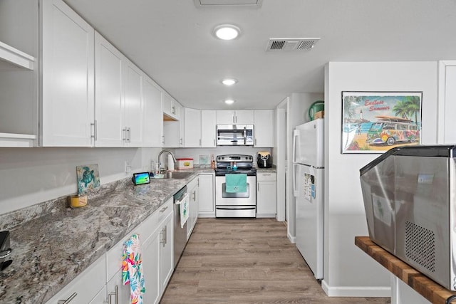 kitchen with appliances with stainless steel finishes, white cabinets, visible vents, and a sink