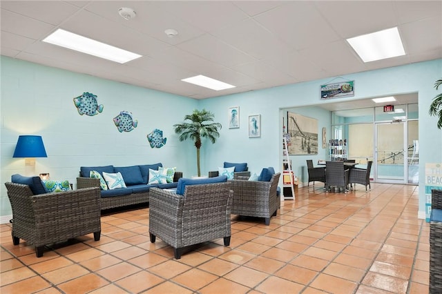 living room with a drop ceiling and light tile patterned flooring