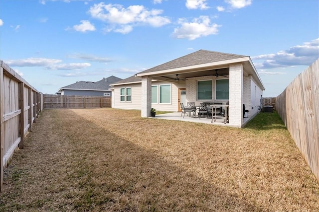 rear view of property with ceiling fan, a yard, and a patio area