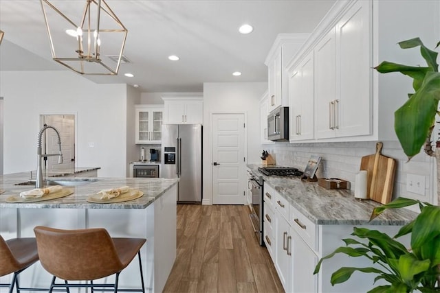 kitchen with stainless steel appliances, light stone countertops, sink, and white cabinets