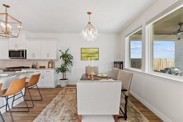 dining space with hardwood / wood-style flooring and ceiling fan with notable chandelier