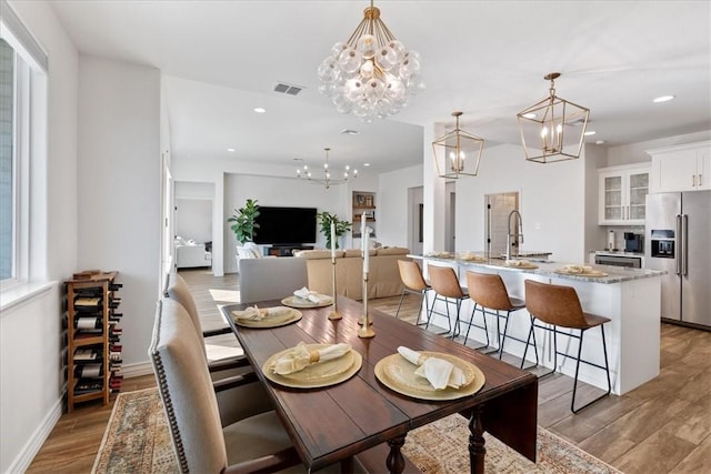 dining area featuring an inviting chandelier, sink, and light wood-type flooring