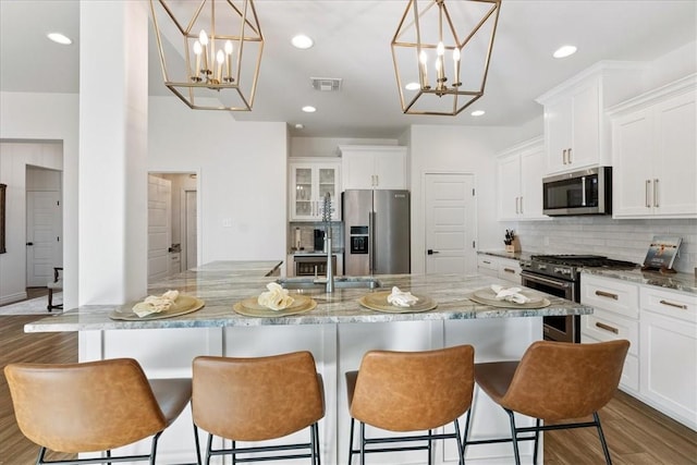 kitchen with high quality appliances, decorative light fixtures, white cabinets, and a spacious island