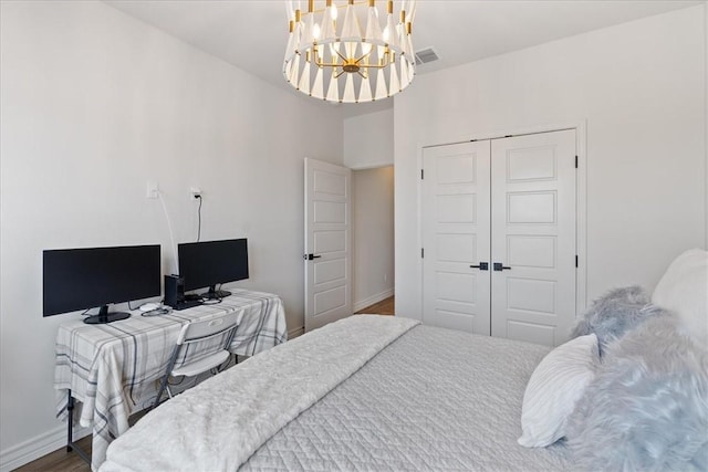 bedroom with a notable chandelier, hardwood / wood-style floors, and a closet