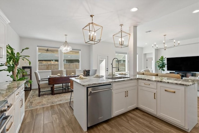 kitchen featuring pendant lighting, white cabinetry, an island with sink, sink, and stainless steel appliances