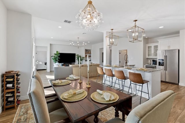 dining area featuring a notable chandelier, light hardwood / wood-style flooring, and sink