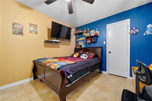 bedroom with ceiling fan, light tile patterned floors, and a textured ceiling