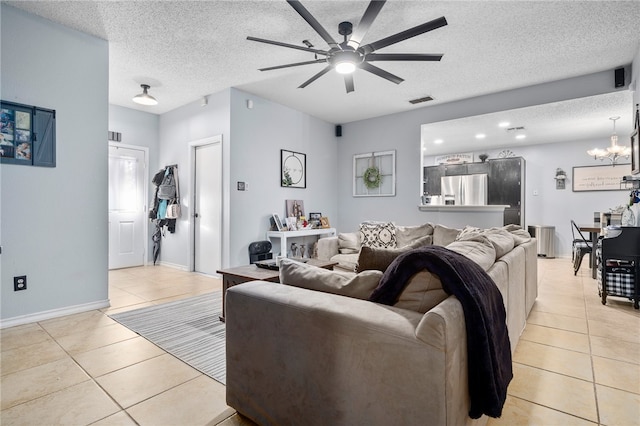 tiled living room with ceiling fan with notable chandelier and a textured ceiling