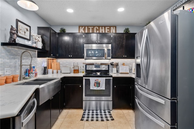 kitchen featuring sink, a textured ceiling, decorative backsplash, light tile patterned flooring, and appliances with stainless steel finishes