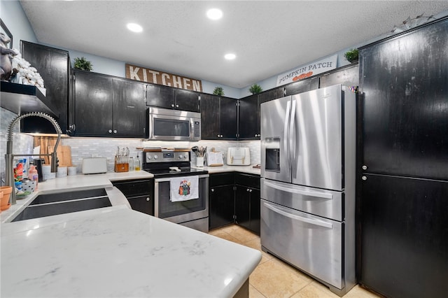 kitchen with sink, stainless steel appliances, a textured ceiling, decorative backsplash, and light tile patterned floors