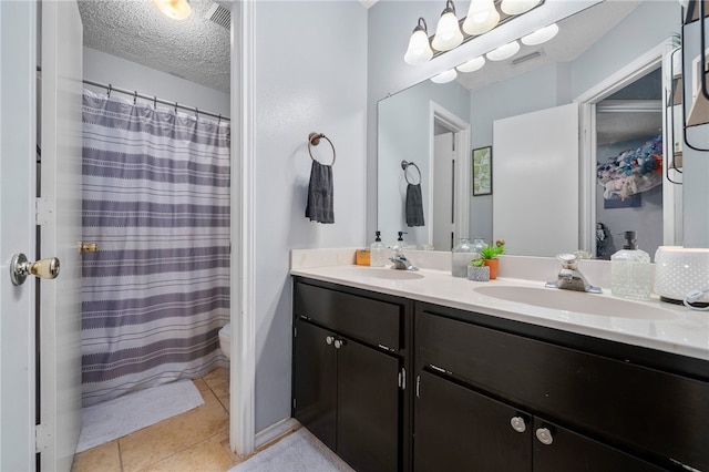 bathroom with tile patterned floors, vanity, a textured ceiling, and toilet