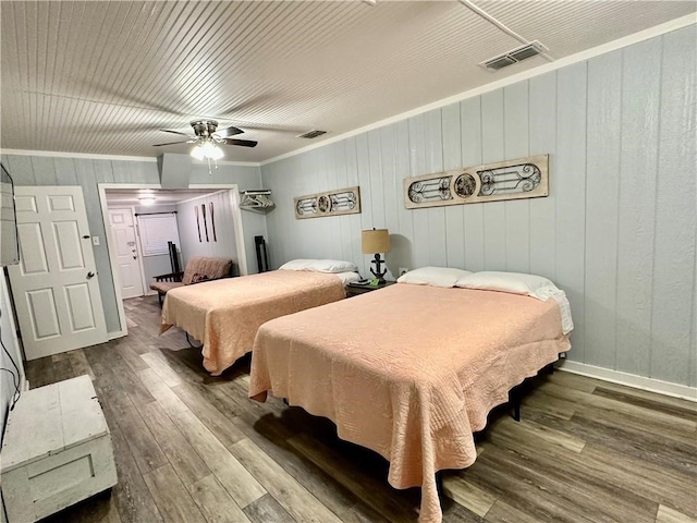 bedroom with hardwood / wood-style flooring, ornamental molding, wood walls, and ceiling fan