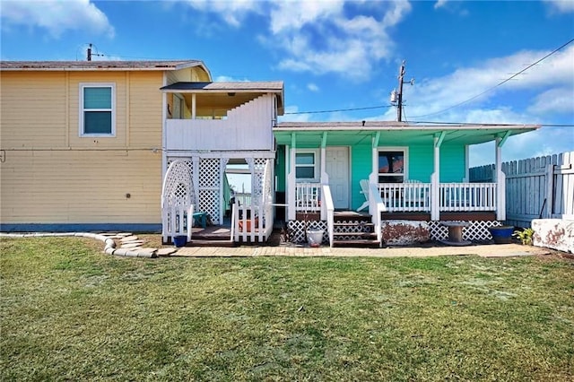 rear view of property with covered porch and a lawn