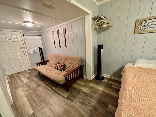 sitting room with wood walls, wood-type flooring, and crown molding