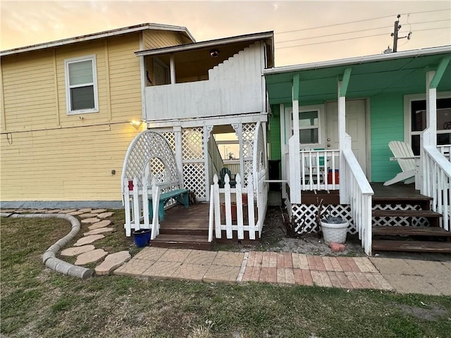 back house at dusk featuring covered porch