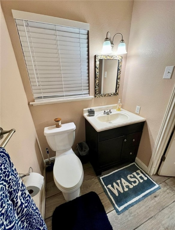 bathroom featuring wood-type flooring, vanity, and toilet