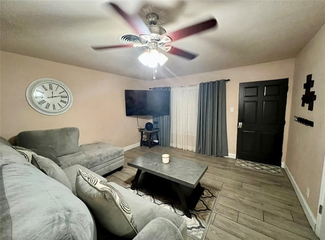 living room featuring ceiling fan, a textured ceiling, and light wood-type flooring