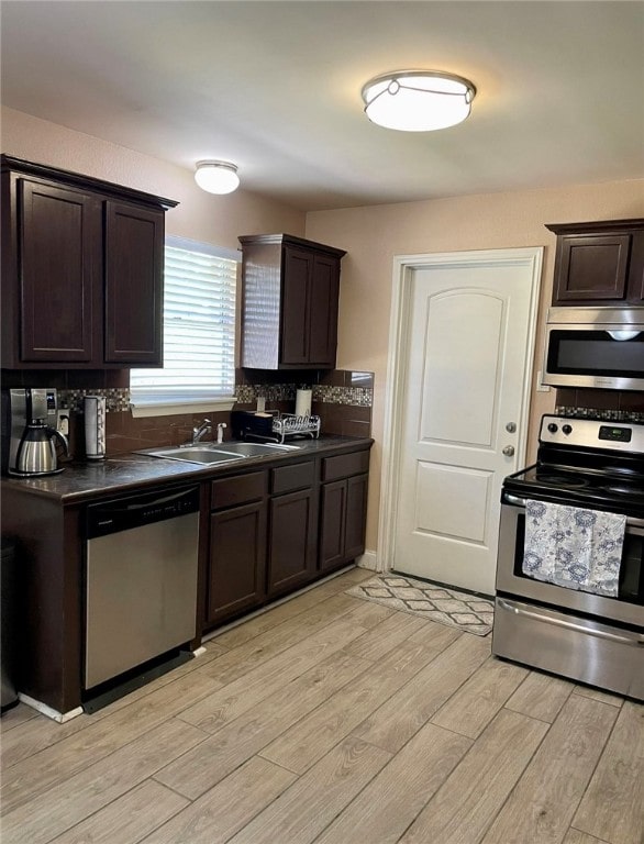 kitchen with dark brown cabinets, stainless steel appliances, and light hardwood / wood-style floors