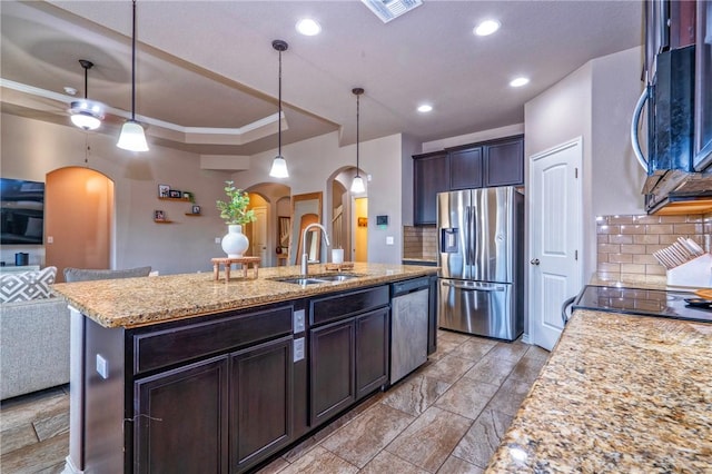 kitchen featuring sink, hanging light fixtures, dark brown cabinets, stainless steel appliances, and a kitchen island with sink