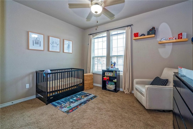 carpeted bedroom featuring a nursery area and ceiling fan