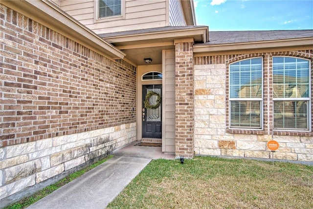 view of exterior entry featuring a lawn