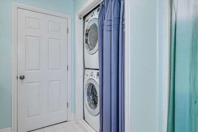 clothes washing area featuring light tile patterned floors and stacked washer and clothes dryer