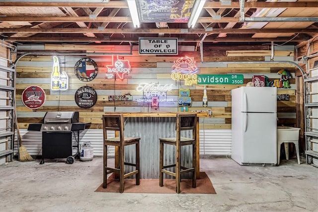 garage with white fridge, wooden walls, and sink