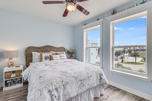 bedroom with multiple windows, wood-type flooring, and ceiling fan