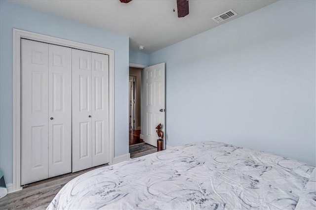 bedroom with ceiling fan, a closet, and wood-type flooring